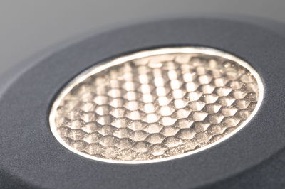 Close-up van ronde LED-lamp met gestructureerd gouden oppervlak en grijze rand voor moderne verlichting