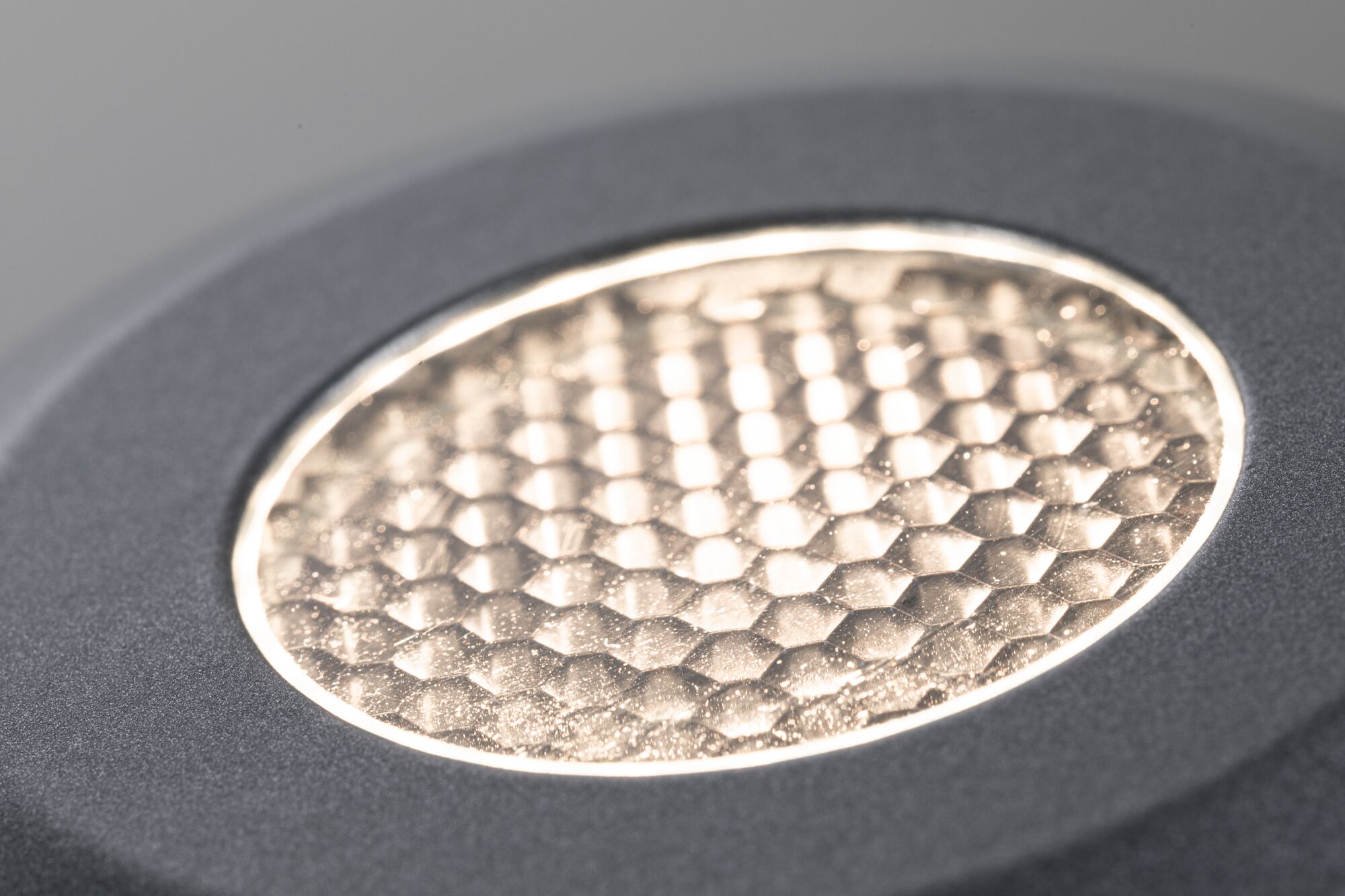 Close-up of round LED light with textured golden surface and grey frame for modern lighting