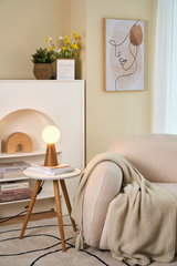 Modern wooden table lamp with round opal white glass in cozy living room with beige sofa.