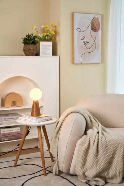 Modern wooden table lamp with round opal white glass in cozy living room with beige sofa.