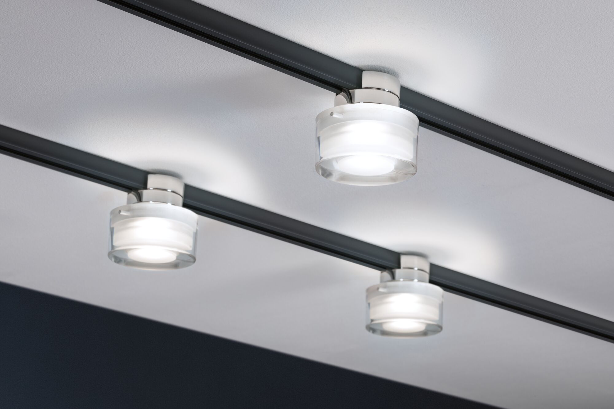 Drei runde LED-Deckenstrahler aus Glas mit schwarzer Schiene für moderne Innenbeleuchtung.