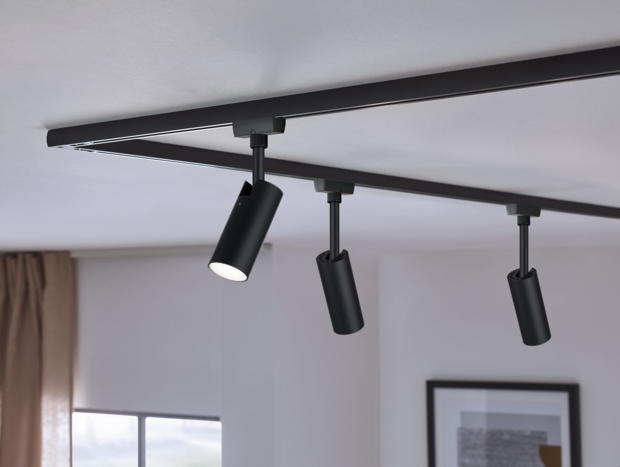 Black metal LED track spotlights mounted on ceiling for modern room lighting solution.