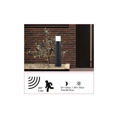Black metal LED outdoor light with motion sensor by red brick wall for garden lighting
