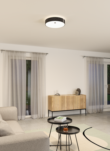 Round ceiling light with black fabric shade and warm white light in modern living room with wooden sideboard.