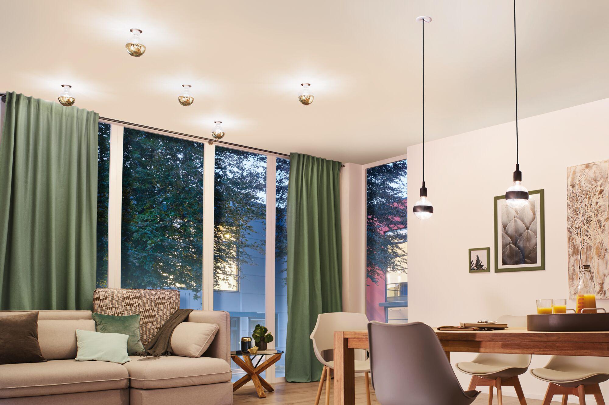 Modern living room with green curtains, wooden dining table, and stylish black and glass pendant lights