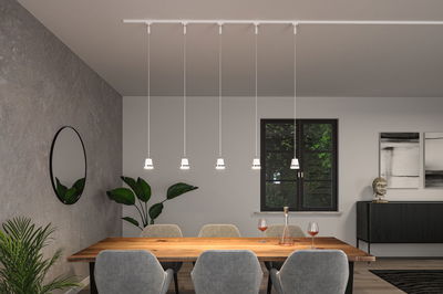 Five white plastic pendant lights above wooden table in modern dining room with grey chairs