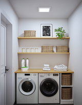 Modern white washing machine and dryer with wooden countertop and wicker baskets in bright laundry room