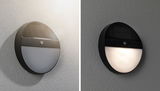 Round black solar wall light with motion sensor, shown mounted on wall day and night