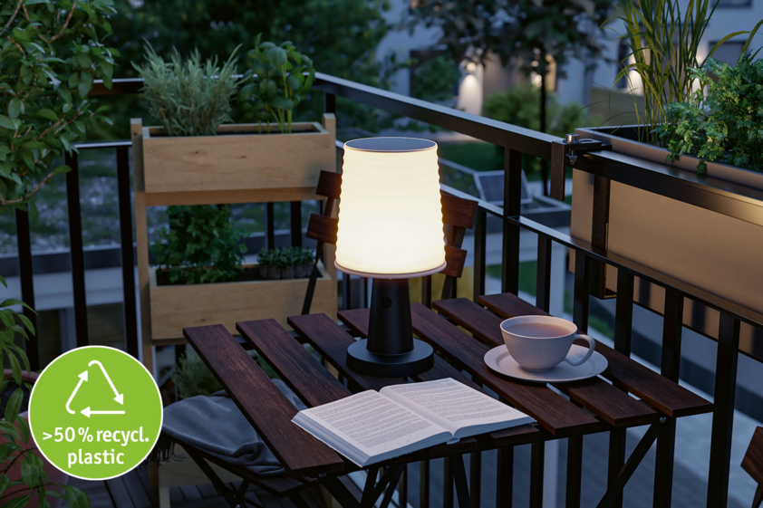 Modern table lamp made from over 50% recycled plastic on balcony with book and cup in evening light