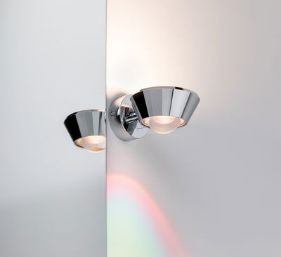 Modern wall spotlight in chrome metal with warm white light and mirror reflection effect.