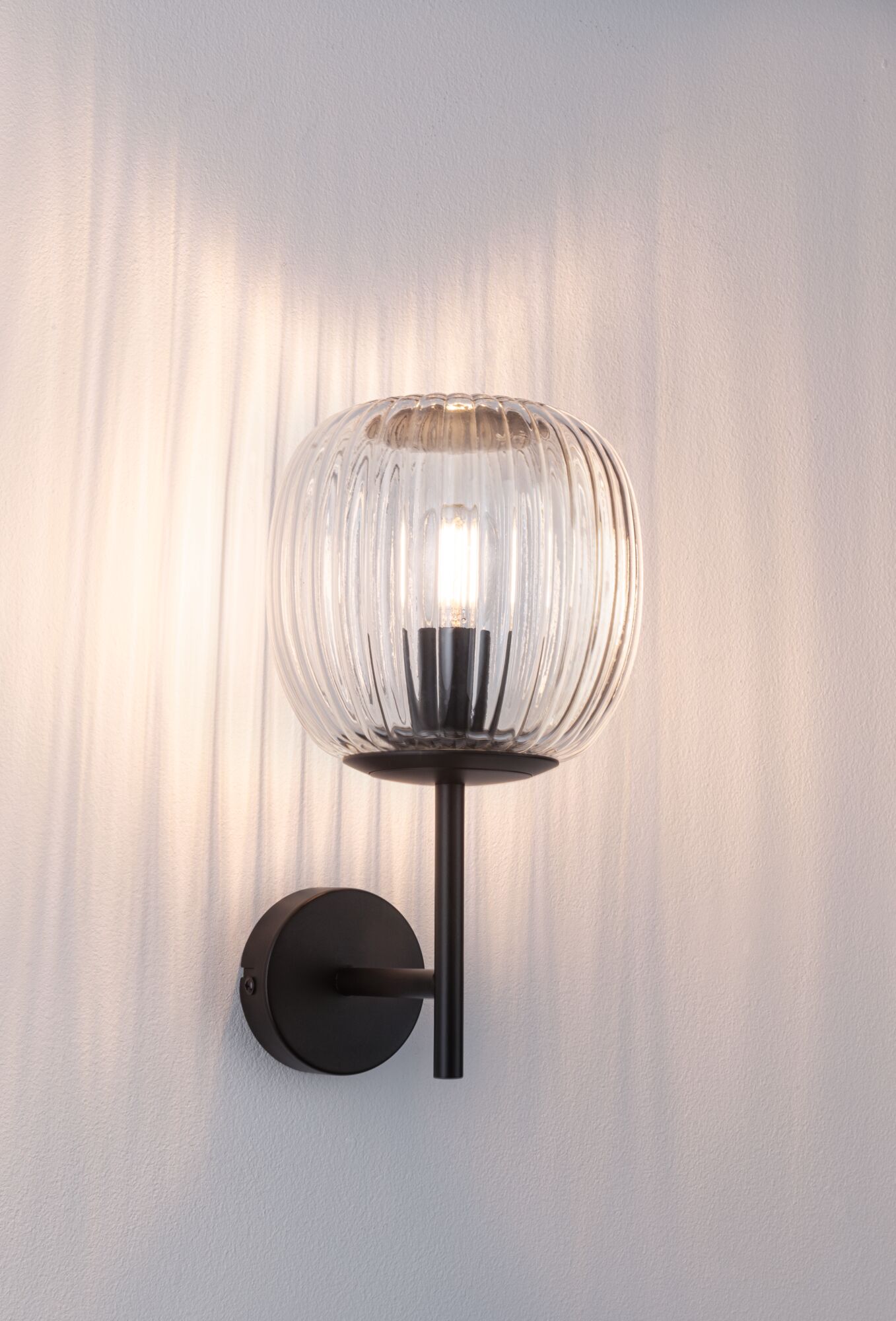 Wall lamp with ribbed clear glass and black metal frame for ambient lighting in modern interiors