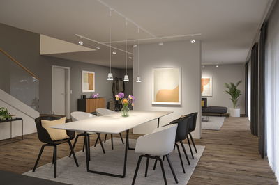 Moderner Essbereich mit weißem Tisch, schwarzen und weißen Stühlen, Holzfußboden und minimalistischer Beleuchtung