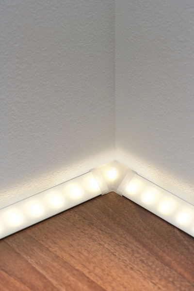LED floor strip lighting with warm white light on white wall and wooden floor for indirect room lighting