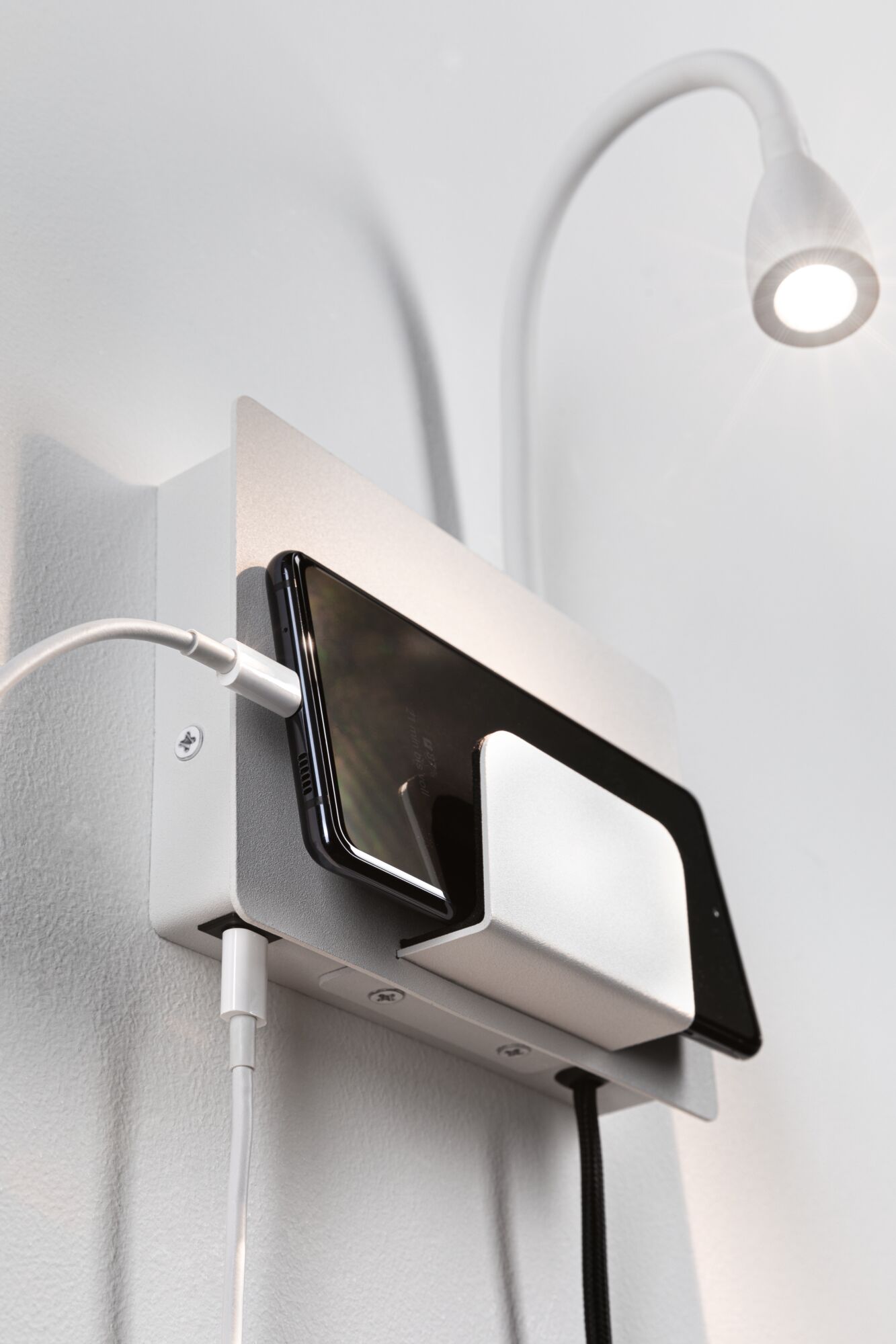 Witte wandhouder met geïntegreerde smartphone-oplaadplek en flexibele LED-leeslamp voor modern interieur