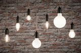 Verschiedene Filament-Glühbirnen mit schwarzer Fassung vor grauer Steinwand für dekorative Beleuchtung