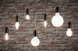 Verschiedene Filament-Glühbirnen mit schwarzer Fassung vor grauer Steinwand für dekorative Beleuchtung