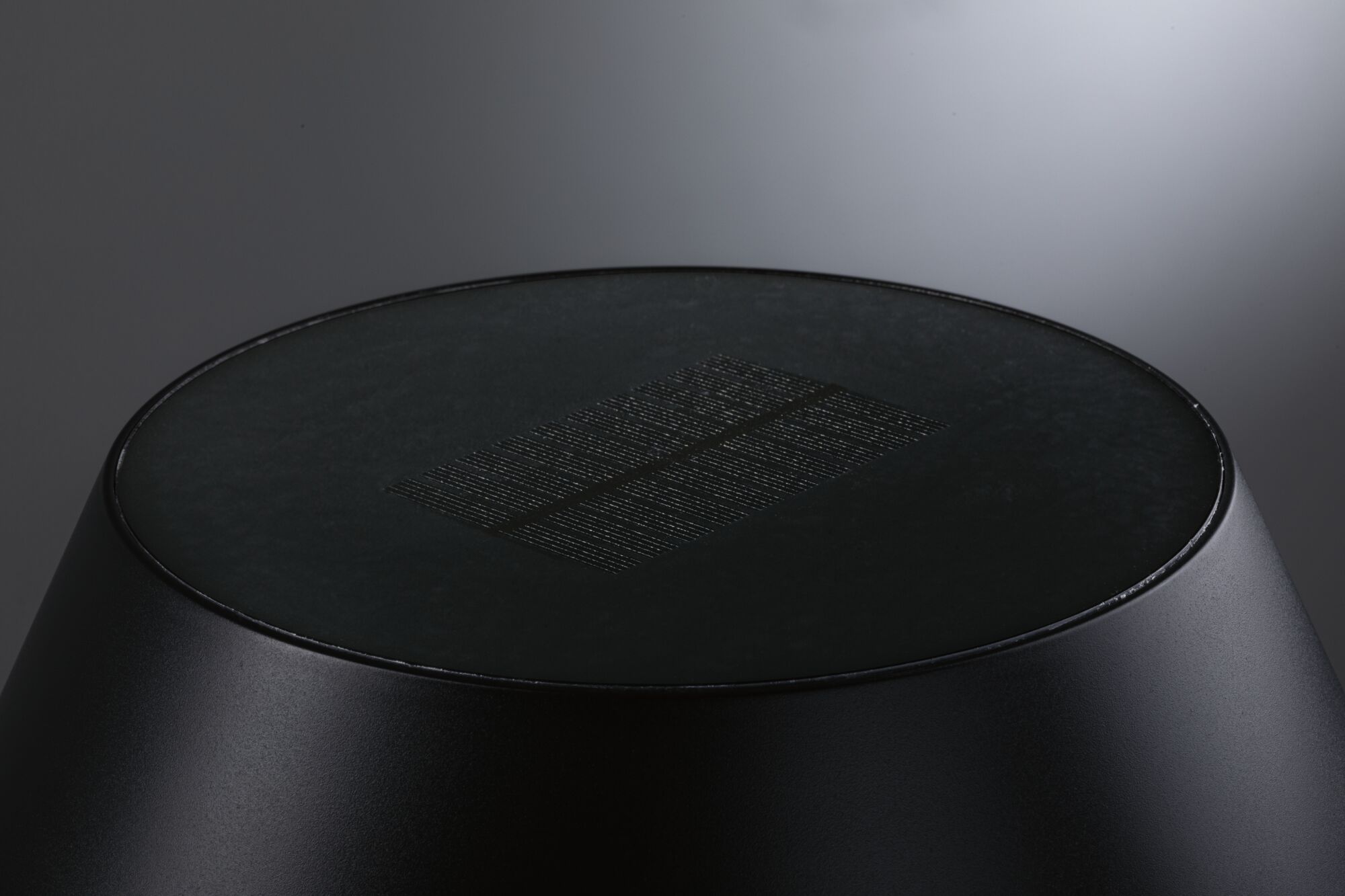 Black round LED light with matte metal housing and textured diffuser for modern indoor lighting