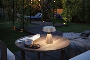 Beleuchtete tragbare Outdoor-Tischlampe in Beige auf Holztisch mit Tasse und Keks im Garten