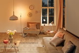 Cozy living room with beige sofa, brown armchair, warm white lamps and decorative clocks on the wall