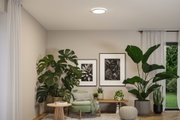 Salon moderne avec plafonnier rond, plantes vertes d'intérieur et fauteuil pastel vert confortable.