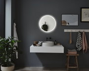 Round illuminated mirror with white frame on grey wall in modern bathroom with sink and towels