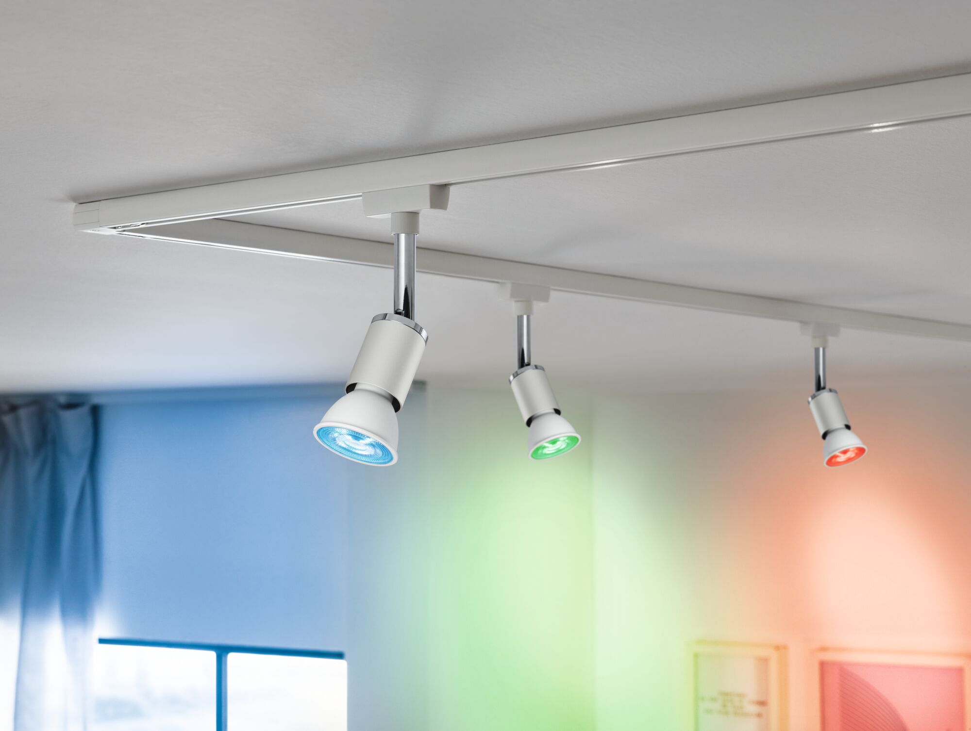 Weiße LED-Schienenstrahler mit blauer, grüner und roter Lichtfarbe an weißer Decke für Akzentbeleuchtung