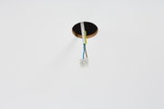 Electrical connection cables with plastic terminal block in white ceiling opening for lighting setup.