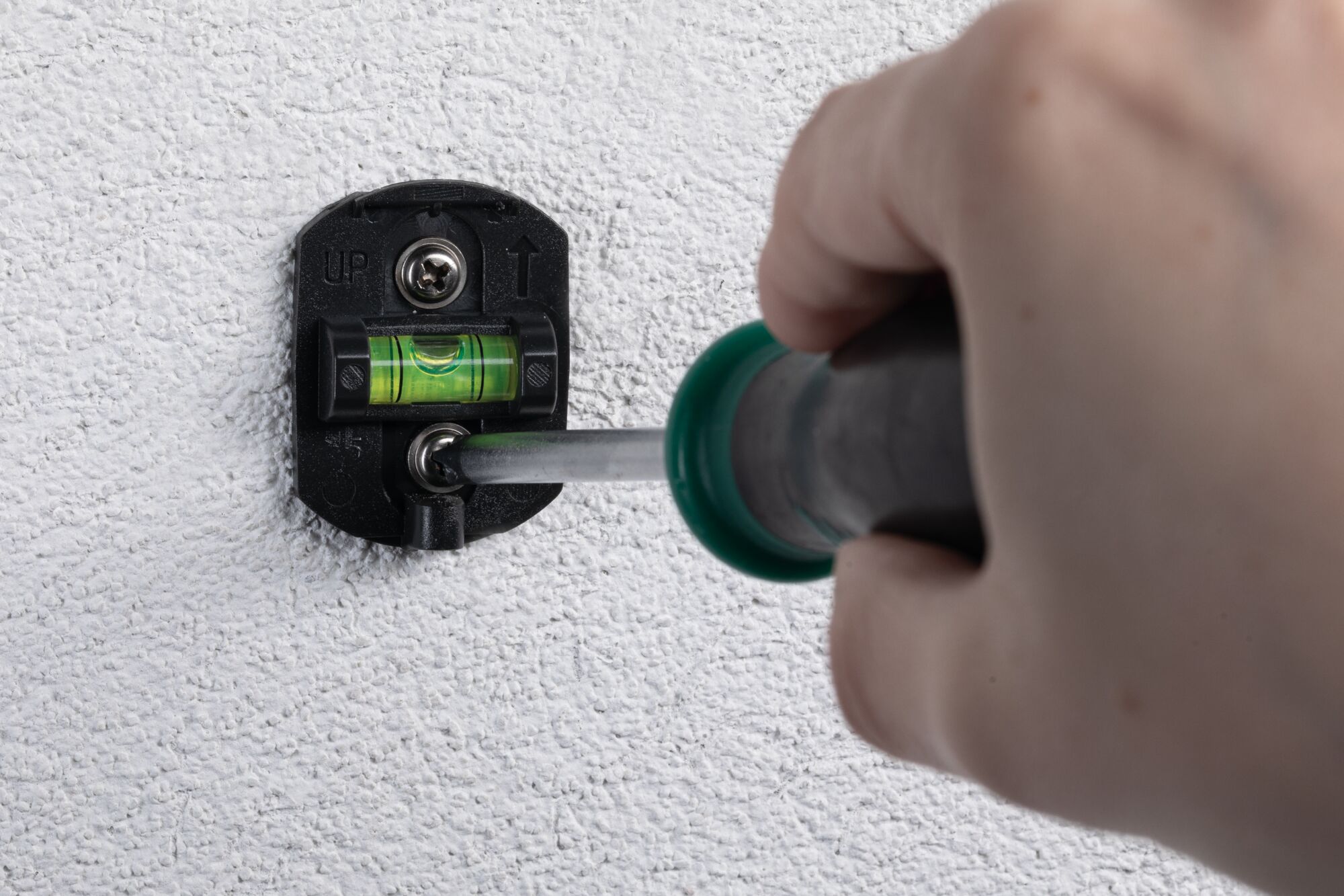 Support mural noir en plastique avec niveau à bulle vert fixé sur mur blanc texturé