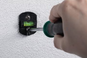 Support mural noir en plastique avec niveau à bulle vert fixé sur mur blanc texturé