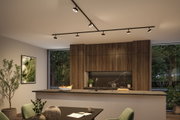 Moderne Küche mit Holzfronten und schwarzer Arbeitsplatte, beleuchtet von schwarzen LED-Deckenstrahlern.
