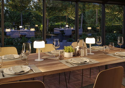 Modern wooden dining table with white LED table lamps in cozy glass-walled dining room setting