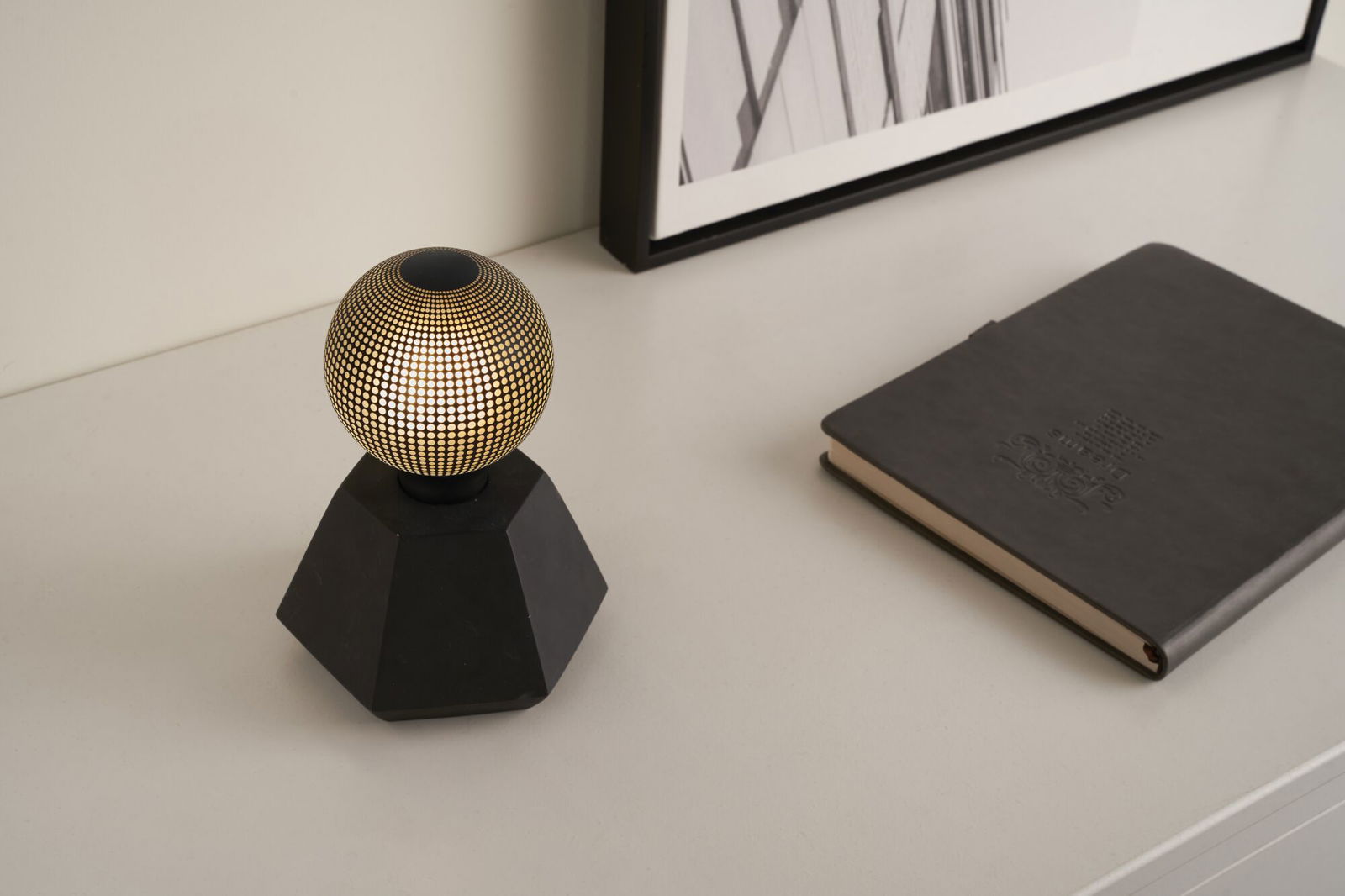 Moderne tafellamp met zwarte zeshoekige voet en gouden bol met stippenpatroon, decoratieve LED-verlichting.