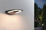 Moderne schwarze LED-Außenwandleuchte mit Bewegungsmelder an weißer Wand im Gartenbereich