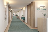 Couloir moderne avec tapis vert, boiseries et appliques murales blanches pour éclairage hôtelier.