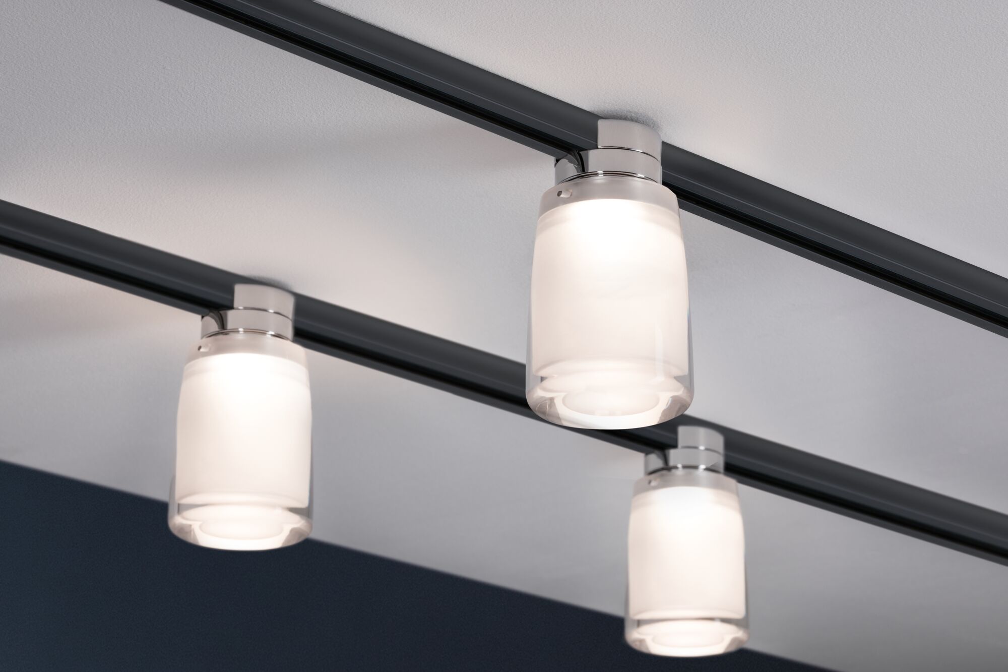 Plafonnier moderne avec trois lampes en verre blanc sur rail noir pour un éclairage élégant