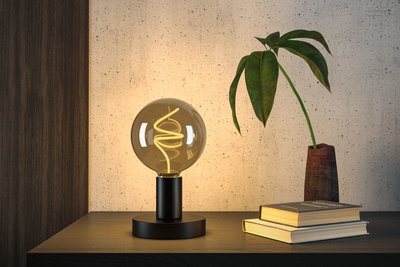 Modern table lamp with black metal base and warm white LED filament in globe glass for living spaces