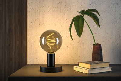 Modern table lamp with black metal base and warm white LED filament in globe glass for living spaces