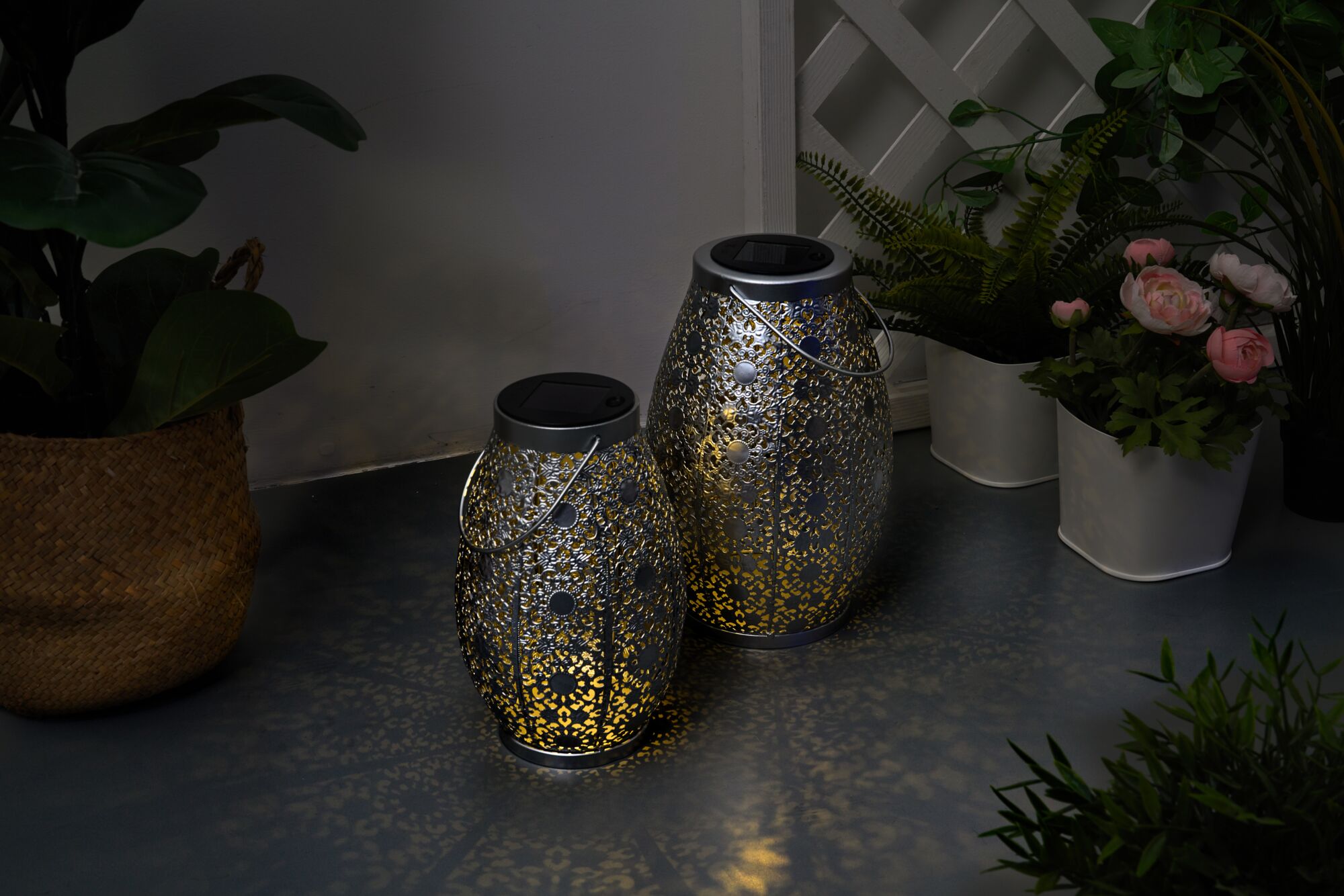 Deux lanternes solaires en métal argenté avec motifs délicats et lumière chaude pour décoration de jardin.