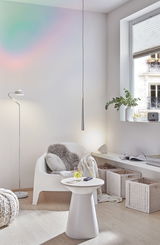 Salon moderne avec fauteuil en plastique blanc, table d'appoint, lampadaire et suspension dans un décor en bois clair