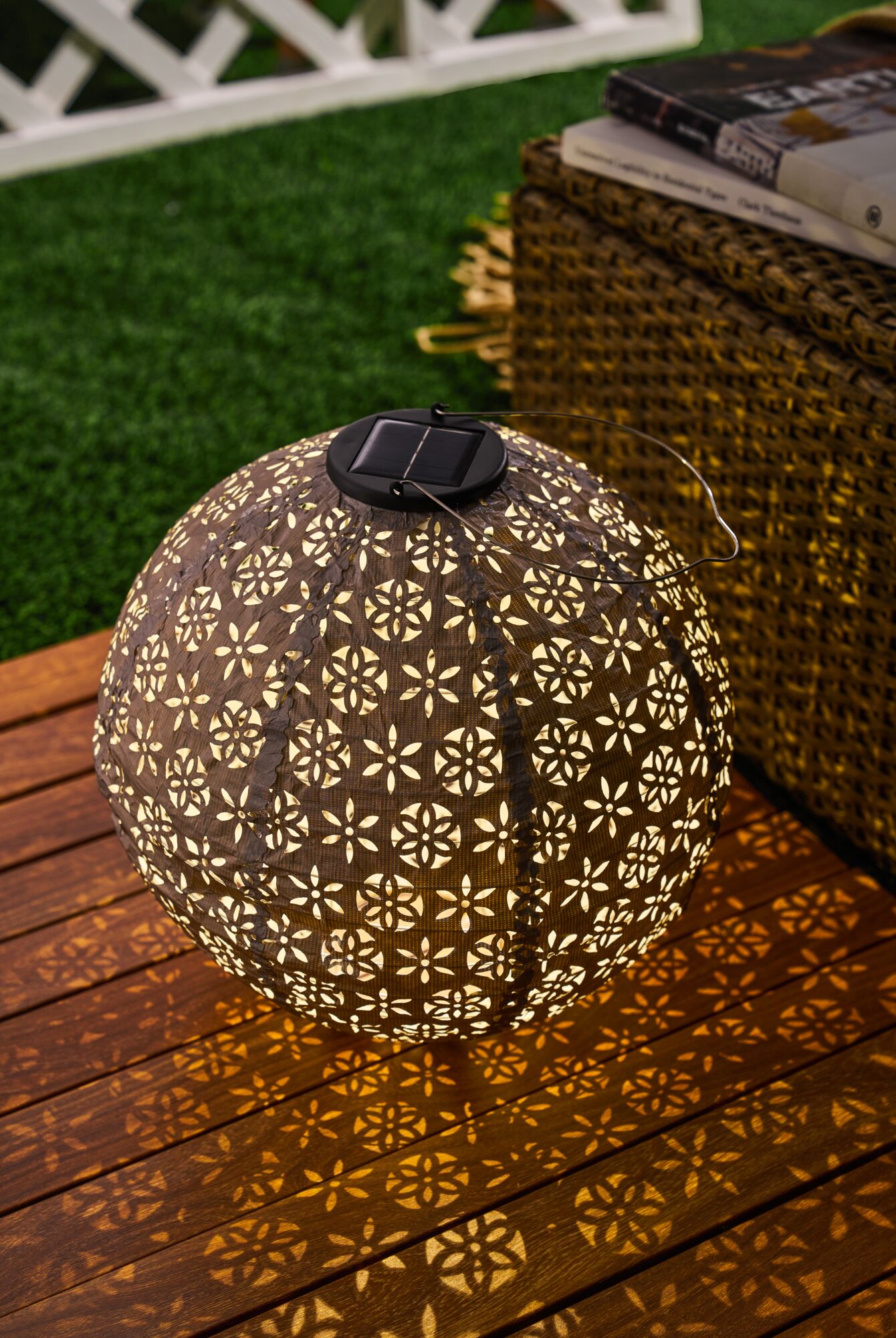 Solar-powered brown metal garden lantern with decorative pattern casting warm light for outdoor use