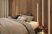 Modernes Schlafzimmer mit Holzlamellenwand und warmem LED-Licht, gemütliches Bett mit Kissen und Decken