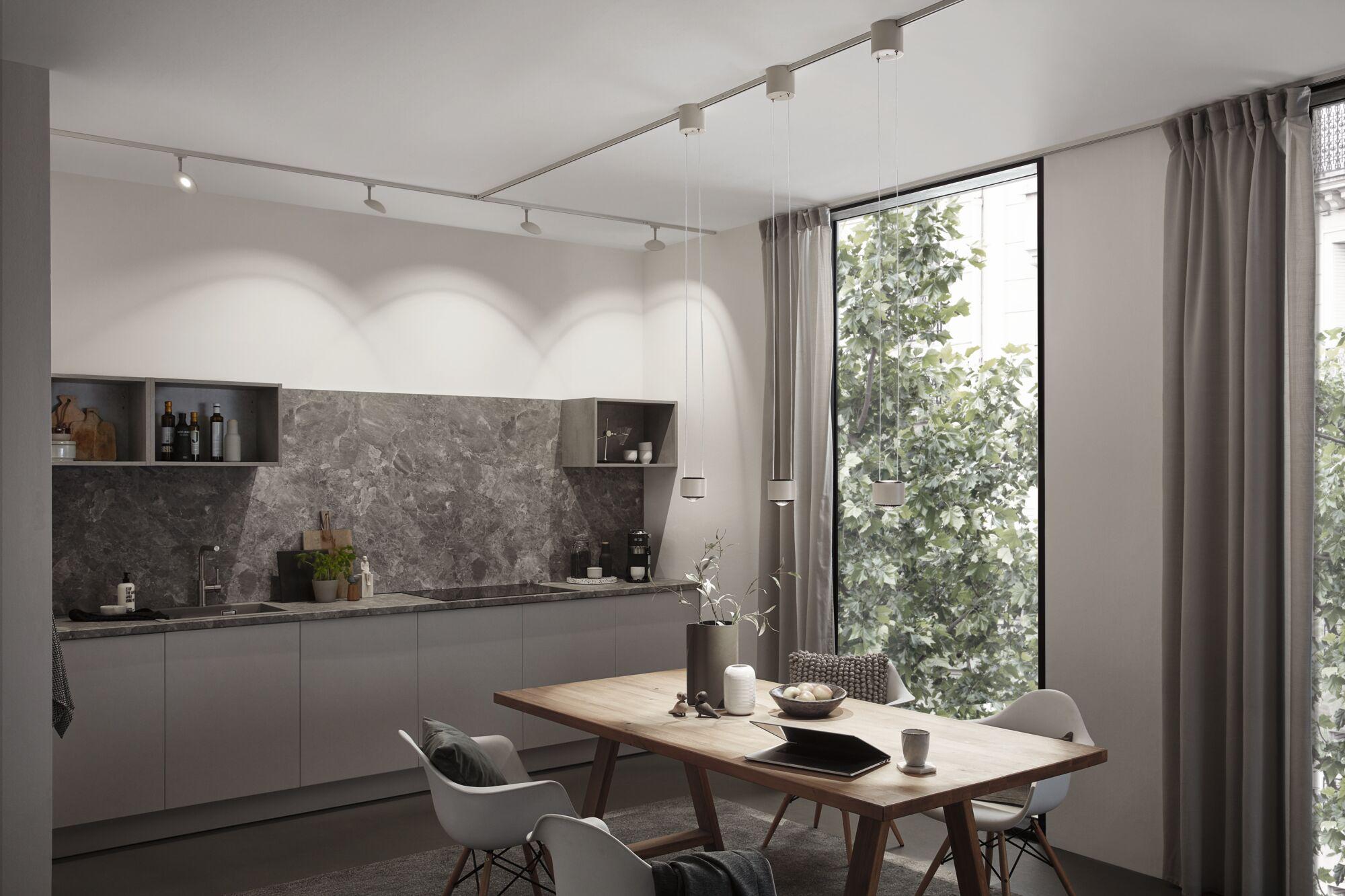 Modern kitchen with grey cabinets, marble countertop and wooden dining table with pendant lights.
