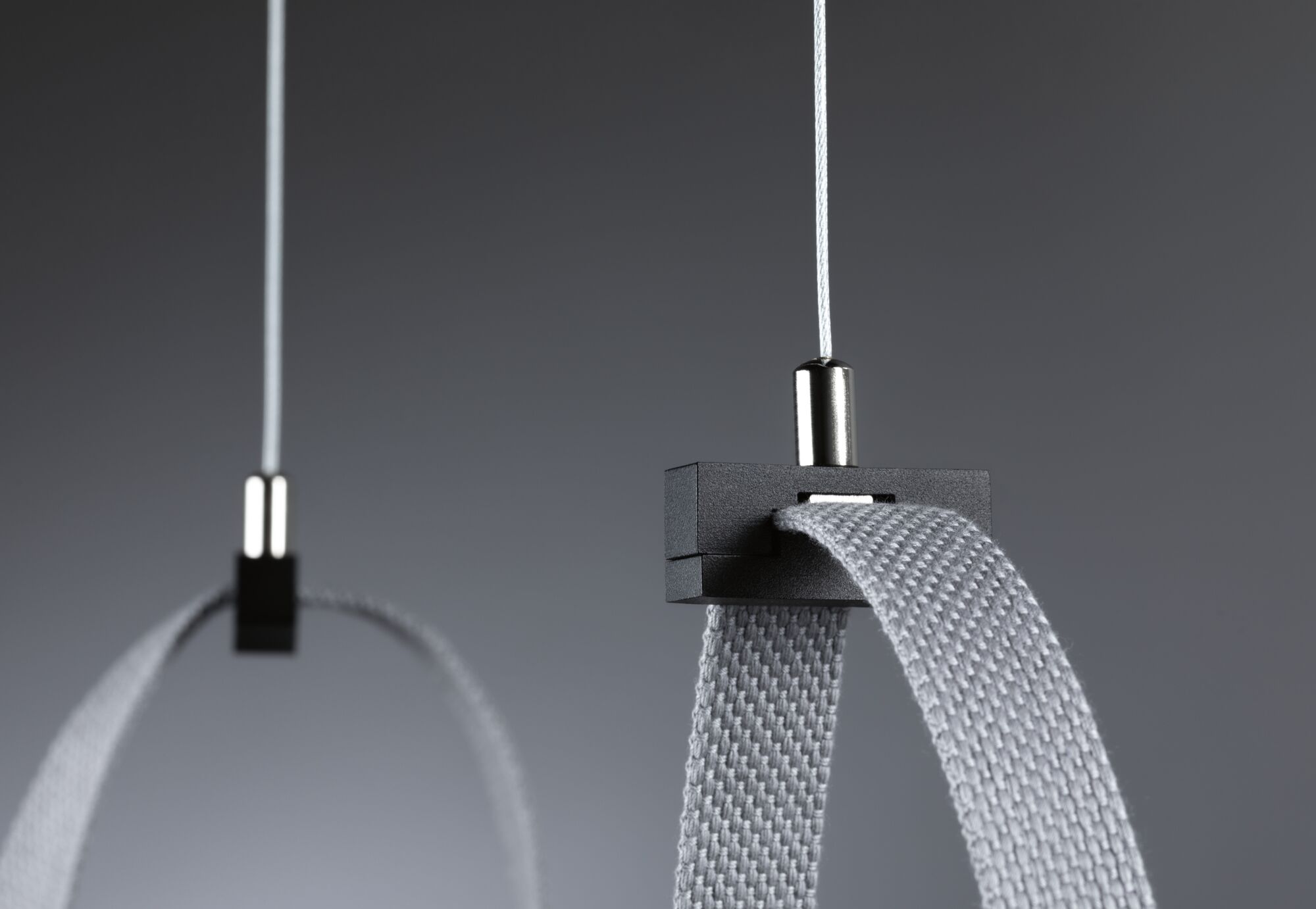 Close-up of grey textile strap with black plastic holder and white cable for lighting system.