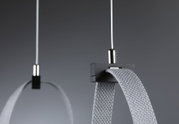 Nahaufnahme von grauem Textilband mit schwarzem Kunststoffhalter und weißem Kabel für Beleuchtungssystem.