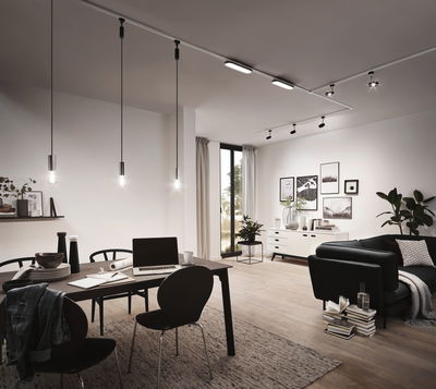 Moderne stue med sorte pendellamper og LED-skinnebelysning i lyst trærum.