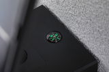 Black casing with built-in compass showing green directions on a grey textured surface