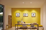 Modern dining room with yellow wall, wooden bench, table, decorative cushions, and LED spot lighting