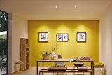 Modern dining room with yellow wall, wooden bench, table, decorative cushions, and LED spot lighting