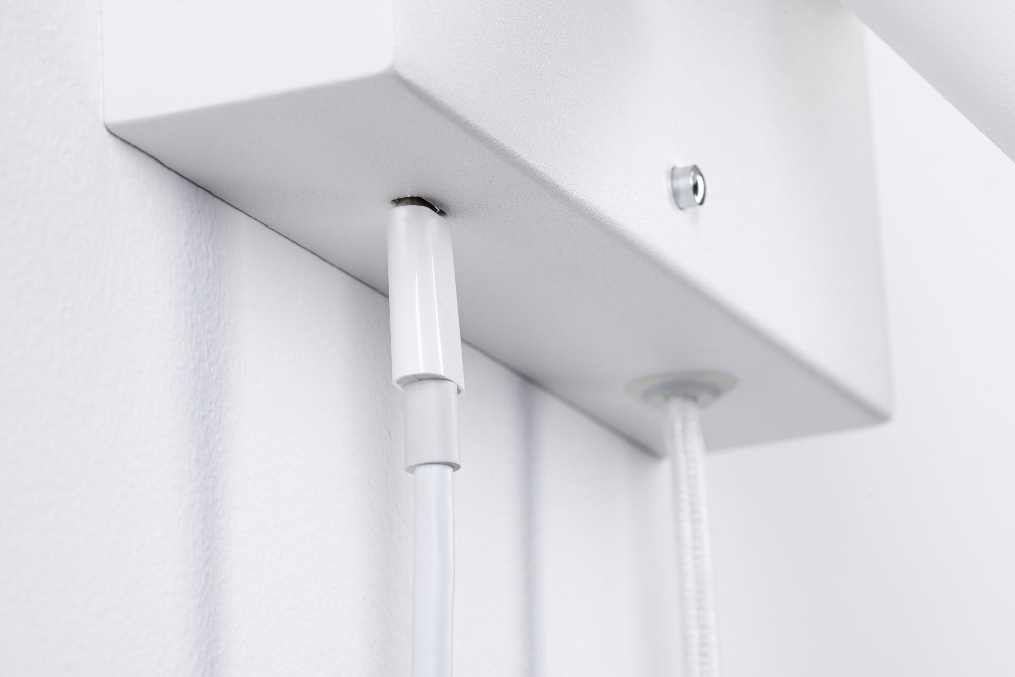 Nahaufnahme eines weißen Kabelanschlusses an einer weißen Metallhalterung für LED-Beleuchtung