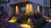 Moderne buitenverlichting met warm wit LED-licht op houten gevel en met stenen geplaveid tuinpad